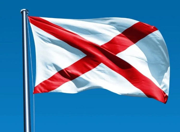 A photo of the flag of Alabama flying on a flagpole with a blue sky in the background.