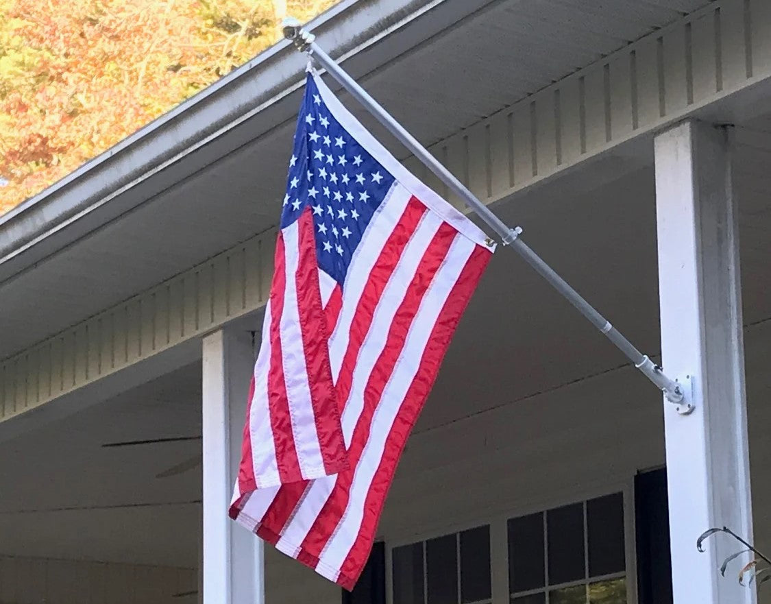 A flagpole and flag attached to a porch